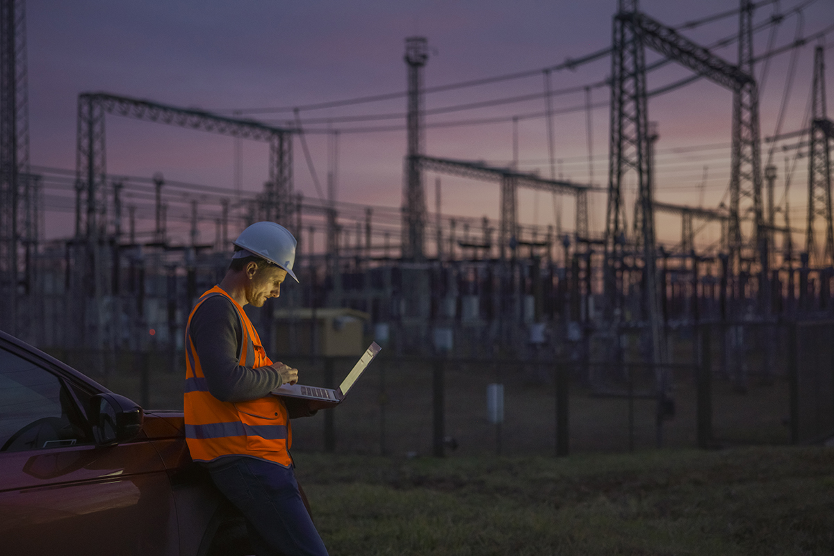 Utility worker checking a substation at sunset image